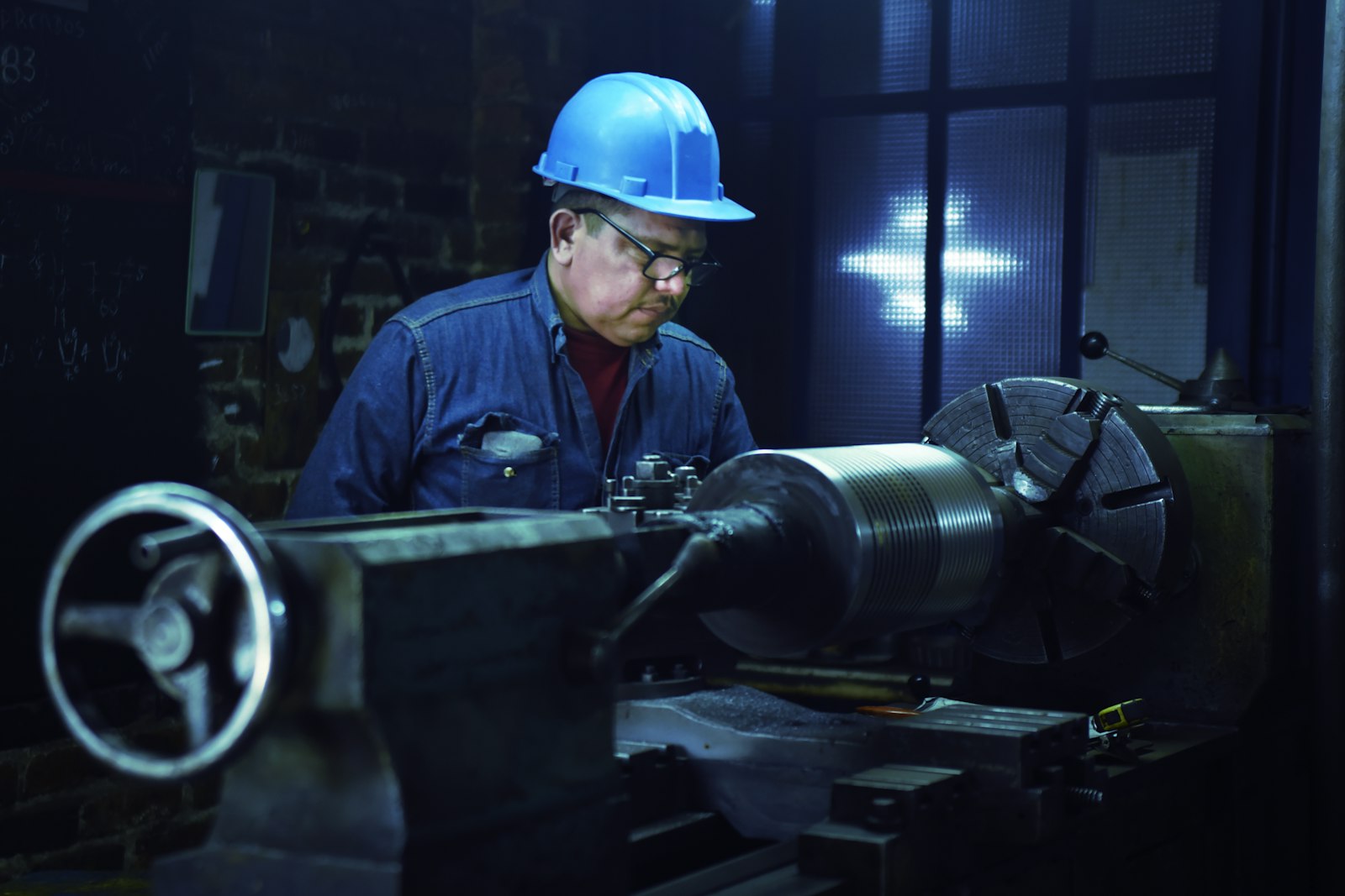 Técnico con casco operando un torno en el mantenimiento de una fábrica